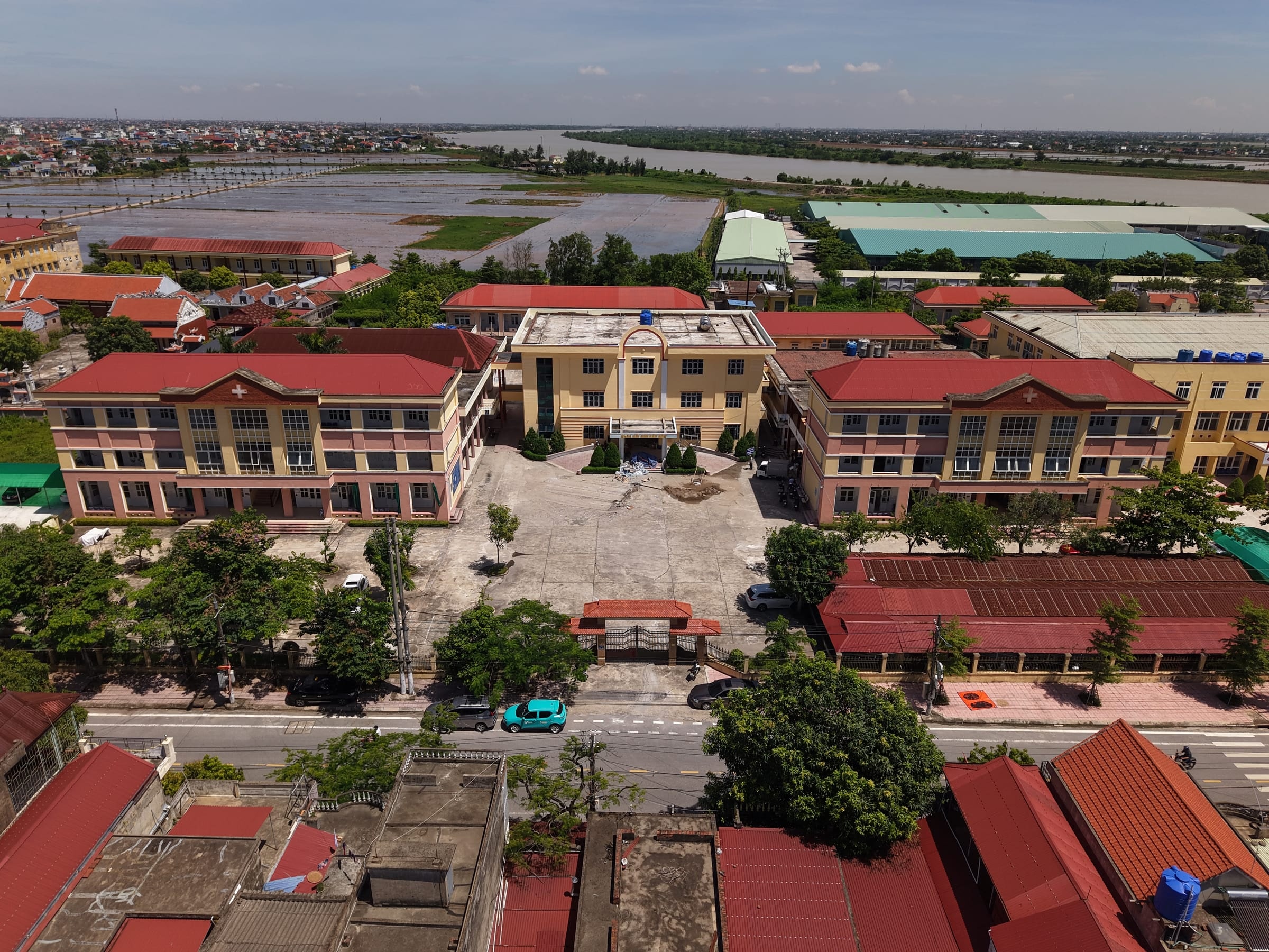 Ảnh flycam trung tâm y tế gần dự án: các khối nhà nhiều tầng mái đỏ quanh sân trong